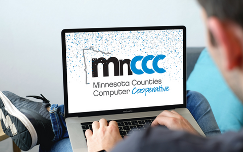 Man using laptop with MnCCC logo on screen covered in blue and gray confetti